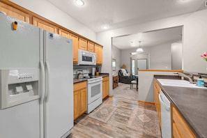 A modern kitchen with a refrigerator, microwave, stove, and wooden cabinets.