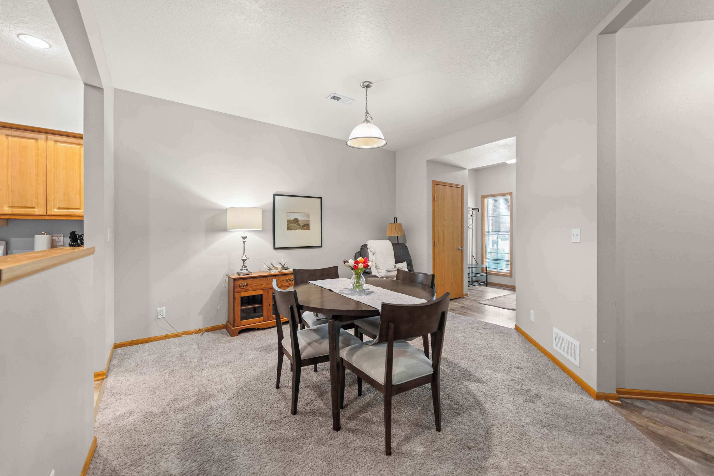 A dining area with a table, chairs, a lamp, and a picture on the wall.