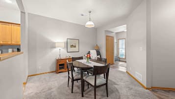 A dining area with a table, chairs, a lamp, and a picture on the wall.