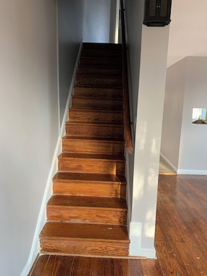 Eine Holztreppe mit weißer Verkleidung und einem kleinen Fenster am obersten Ende.