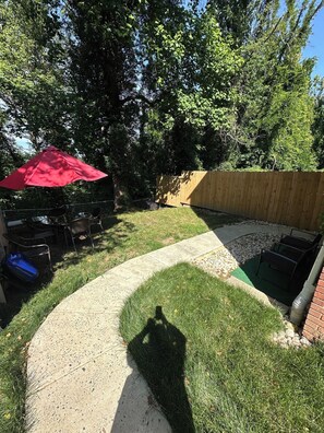 Ein Garten mit Terrasse, Schwimmbecken und Holzzaun.