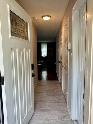 A hallway with white doors, a ceiling light, and a dark room at the end. - Serene 3-Bedroom townhouse where location meets comfort and convenience. (Woodlawn)