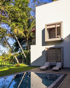 A modern house with a swimming pool, two lounge chairs, and a large window. - ONA Garden Villa: Deluxe Double/Twin Room (Galle)