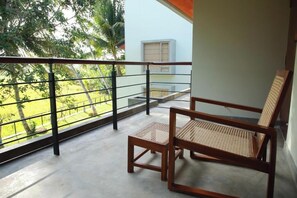 A balcony with a view of a garden and a building. There are two wooden chairs with woven seats. - ONA Garden Villa: Deluxe Double/Twin Room (Galle)