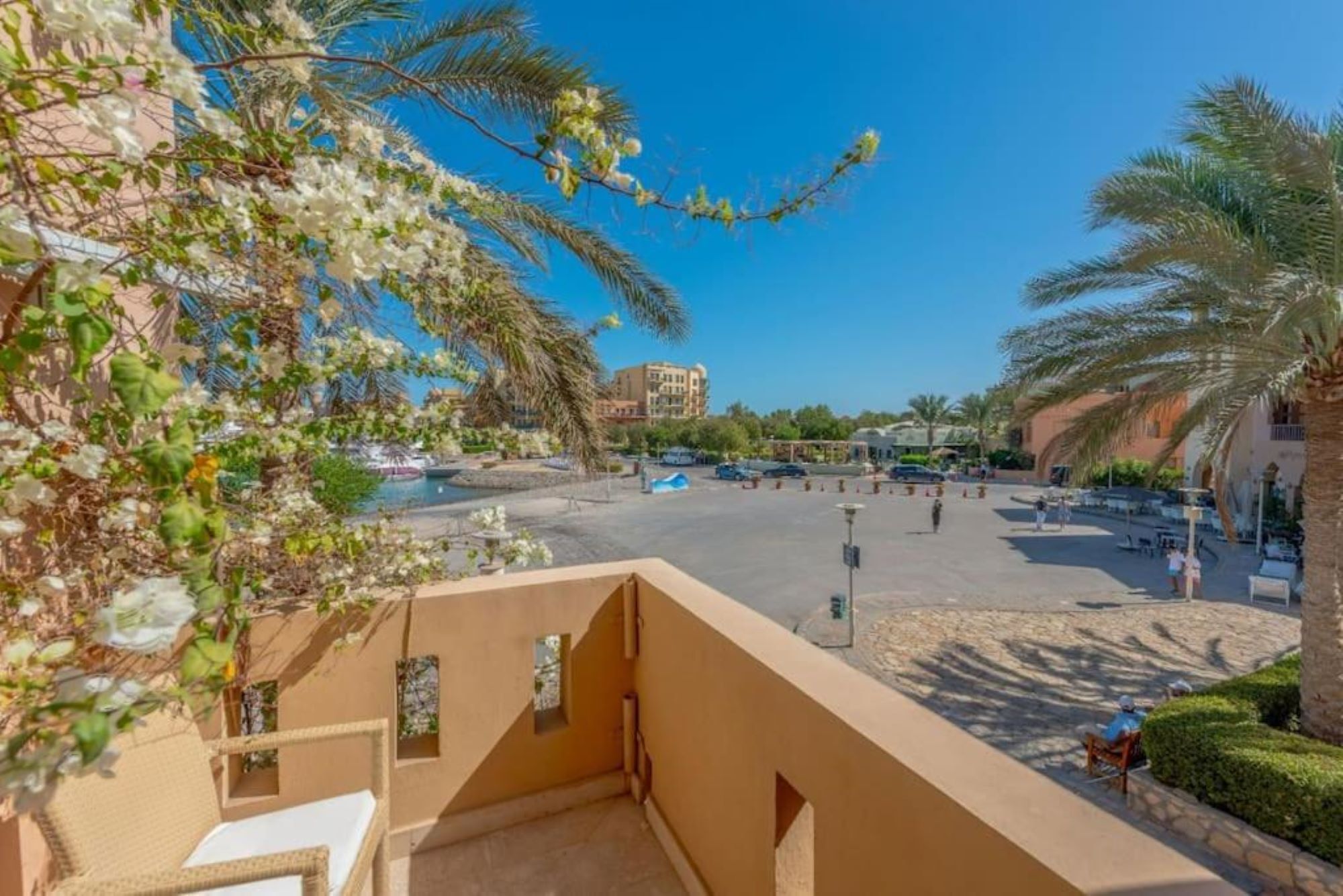 A hotel courtyard with palm trees, a pool, and a building in the background.