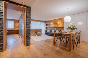 A modern living room with a sofa, coffee table, and dining area with chairs. - Beaulieu - Inspiringplaces Zermatt (Zermatt)