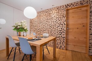 Een moderne eethoek met een houten tafel, stoelen en een decoratieve wand.