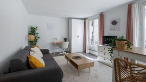A modern living room with a sofa, coffee table, and a TV on a stand. - Studio in Pigalle - Moulin Rouge and Montmartre (Paris)