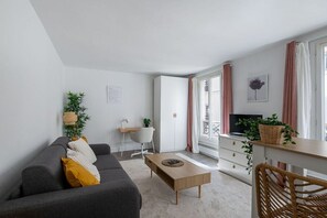 Ein modernes Wohnzimmer mit einer Couch, einem Couchtisch und einem Fernseher auf einem Schrank.
