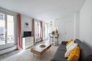 Un salon moderne comprenant un canapé, une table basse, un téléviseur et un coin repas avec des chaises et une table.
