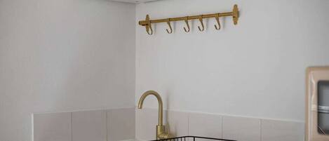 A kitchen with a white countertop, a gold faucet, and a black drying rack.