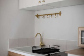 A kitchen with a white countertop, a gold faucet, and a black drying rack. - Studio in Pigalle - Moulin Rouge and Montmartre (Paris)