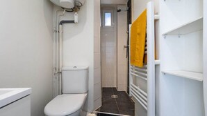 A bathroom with a toilet, a shower area, and a towel rack. - Studio in Pigalle - Moulin Rouge and Montmartre (Paris)
