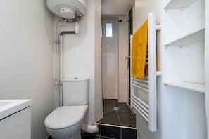 Ein Badezimmer mit Toilette, einer Duschkabine und einem Handtuchhalter.