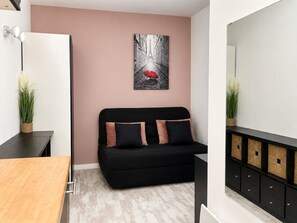Ein modernes Wohnzimmer mit einem schwarzen Sofa, einem Holztisch, einem weißen Schrank und einem Gemälde einer roten Plane an der Wand.