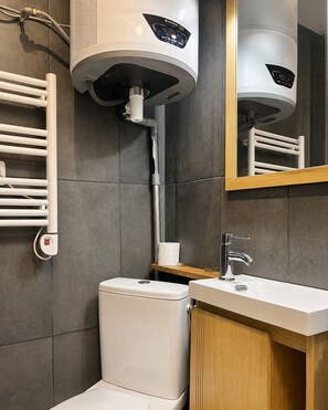 Ein modernes Badezimmer mit Toilette, Waschbecken und einer großen Lüftungsanlage.