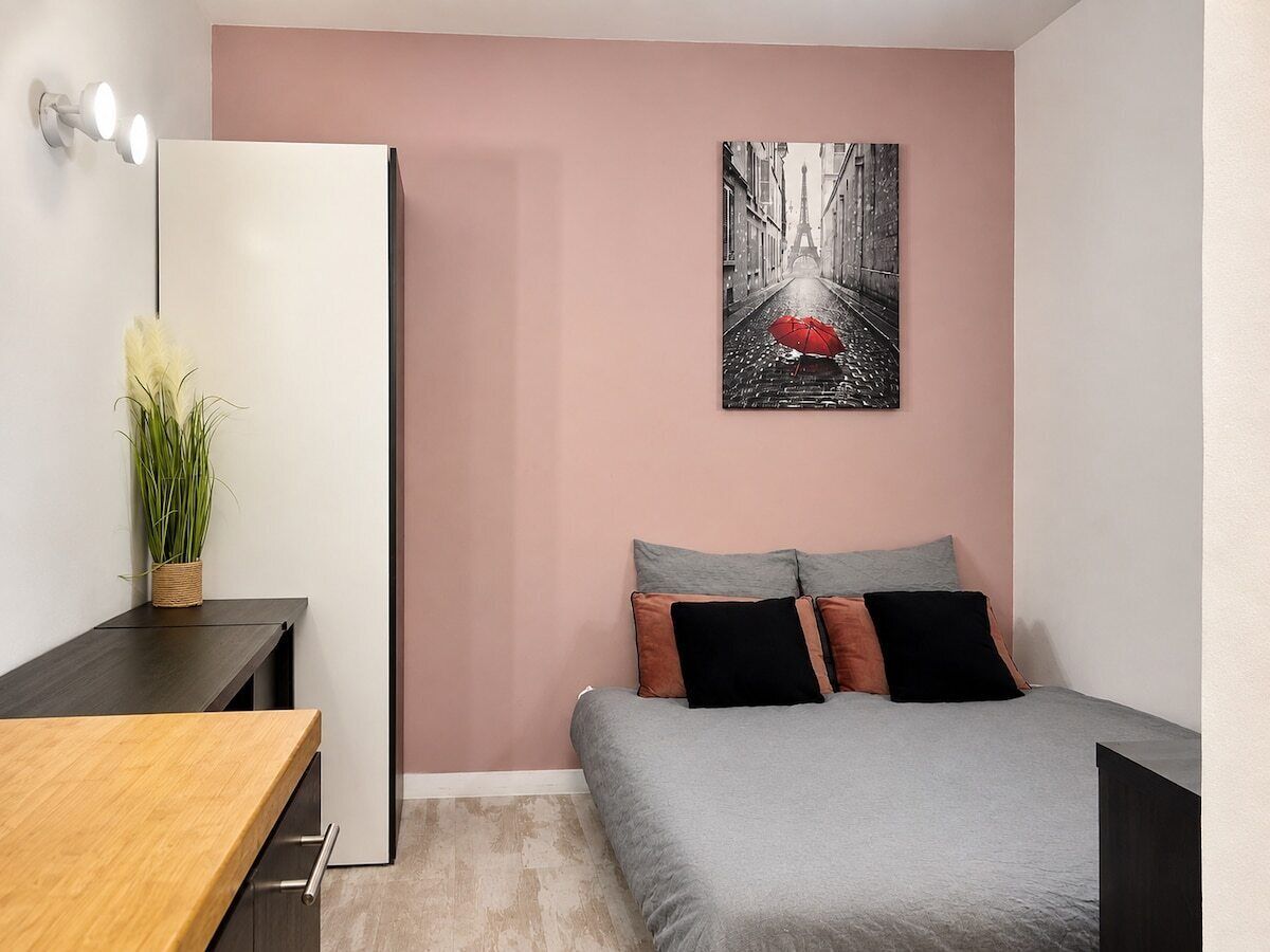 A bedroom with a bed, bedside table, and a wall-mounted artwork.