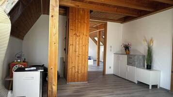 A spacious room with a high ceiling, wooden beams, and a central wooden column.