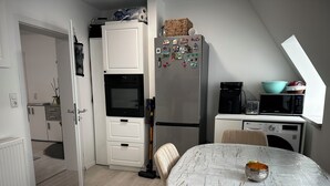 A compact kitchen with a microwave, refrigerator, and a small dining area with a table.