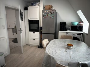 A compact kitchen with a microwave, refrigerator, and a small dining area with a table.