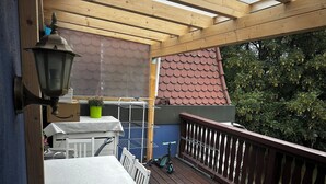 A wooden deck with a table and chairs, a lantern, and a potted plant.