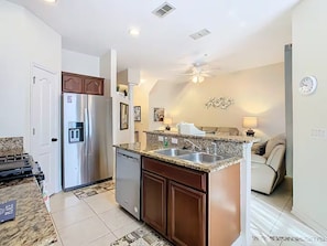 A modern kitchen with granite countertops, stainless steel appliances, and a dining area with a sofa. - Reunion Resort Getaway Close to Disney World. (Kissimmee)