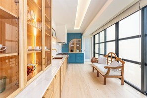A modern kitchen with wooden cabinets, a marble countertop, and a large window. - Foz do Douro Luxury Penthouse , Rooftop Terrace & Bathtub (Porto)