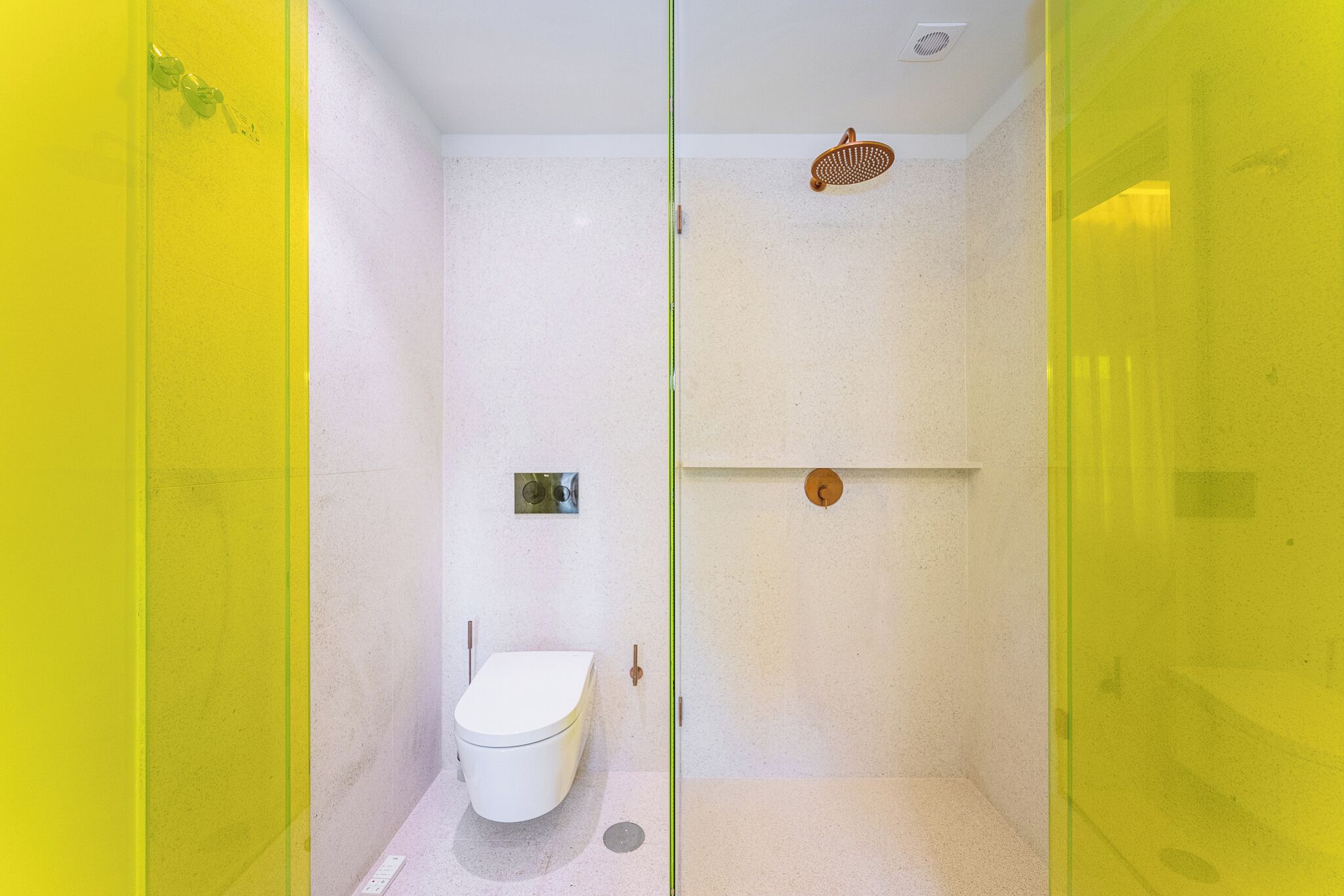 Une salle de bain avec des toilettes blanches, une douche dotée d’un pommeau de douche à pluie et un porte-serviettes.