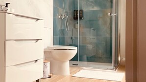 Ein modernes Badezimmer mit einer Duschkabine aus Glas, einer weißen Toilette und einem Marmor-Waschtisch.