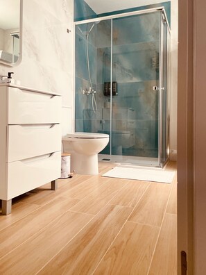Ein modernes Badezimmer mit einer Duschkabine aus Glas, einer weißen Toilette und einem Marmor-Waschtisch.