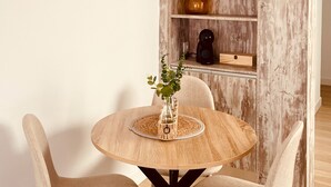 Ein runder Holztisch mit einer gewebten Tischmatte, umgeben von zwei beigen Stühlen mit gewebten Sitzflächen.