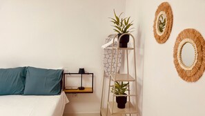 Un dormitorio con una cama, una estantería con plantas y espejos decorativos.