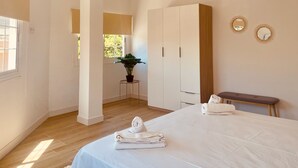 A hotel room with a bed, a bench, a small table with a plant, and a mirror on the wall. - Click&Guest - Doctoral Urbana 2 (Santa Lucía de Tirajana)
