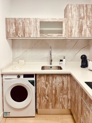 Eine kompakte Küche mit Einbauwaschmaschine, Spüle und Holzschränken.