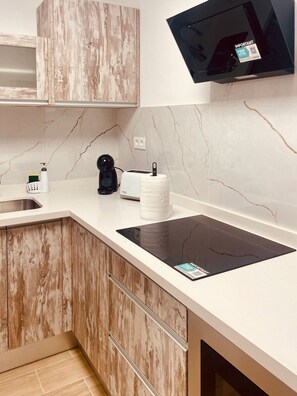 Eine moderne Küche mit Einbauherd, Kaffeemaschine, Toaster und Seifenspender.
