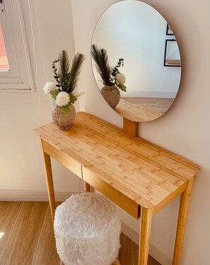 Ein Holztisch mit einem runden Spiegel und einer Vase mit Blumen.