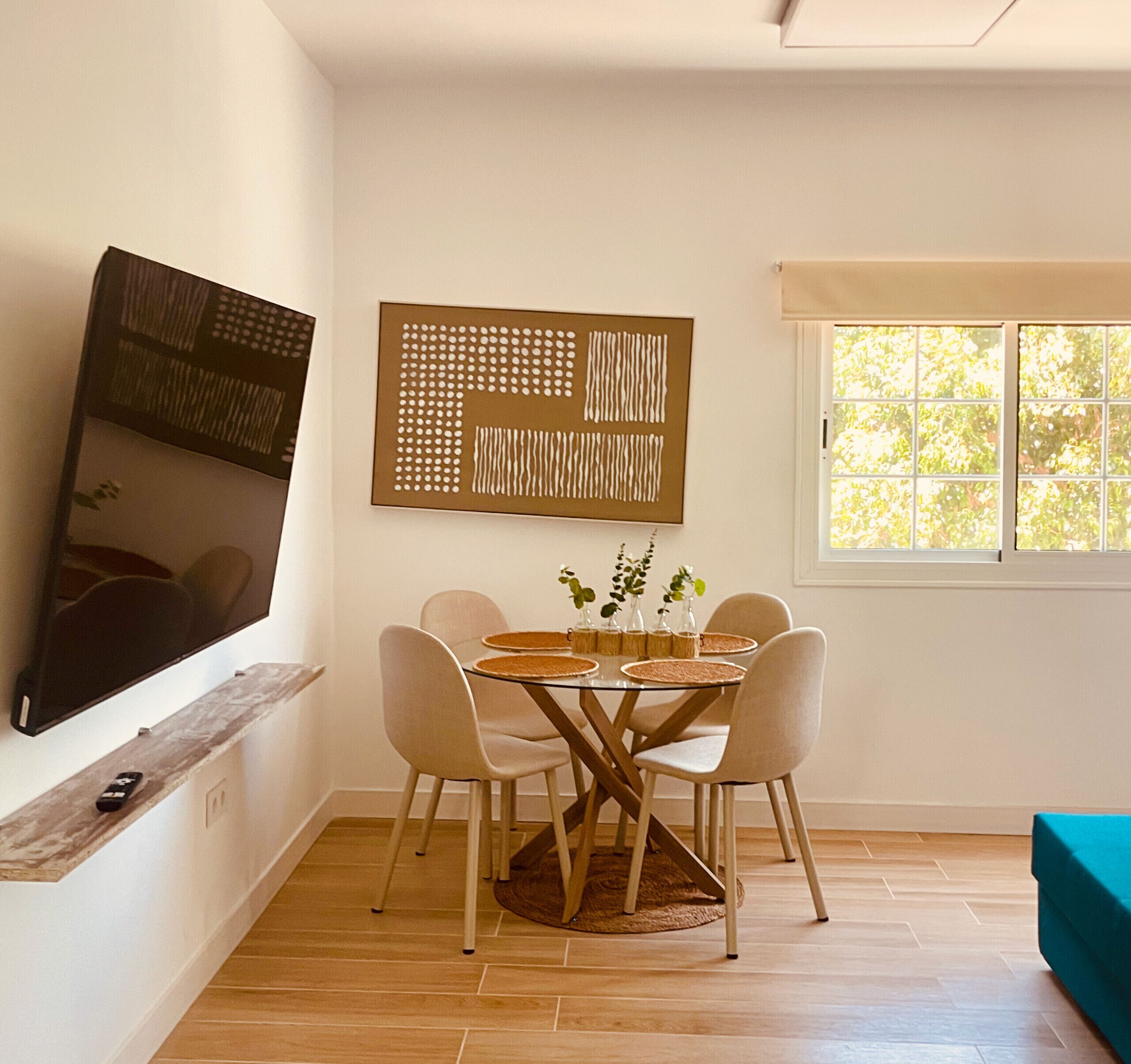 A dining area with a table, chairs, a television, and artwork on the wall.