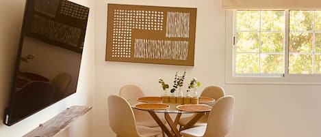 Un espace repas comprenant une table, des chaises, un téléviseur et des œuvres d’art accrochées au mur.