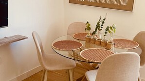 A dining area with a glass table surrounded by four chairs, a woven placemat, and a decorative wall piece above. - Click&Guest - Doctoral Urbana 2 (Santa Lucía de Tirajana)