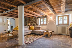 A cozy living room with a stone wall, a wooden ceiling, a sofa, a coffee table, and a window.