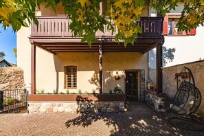 A building with a stone facade, a wooden balcony, and a hanging chair.