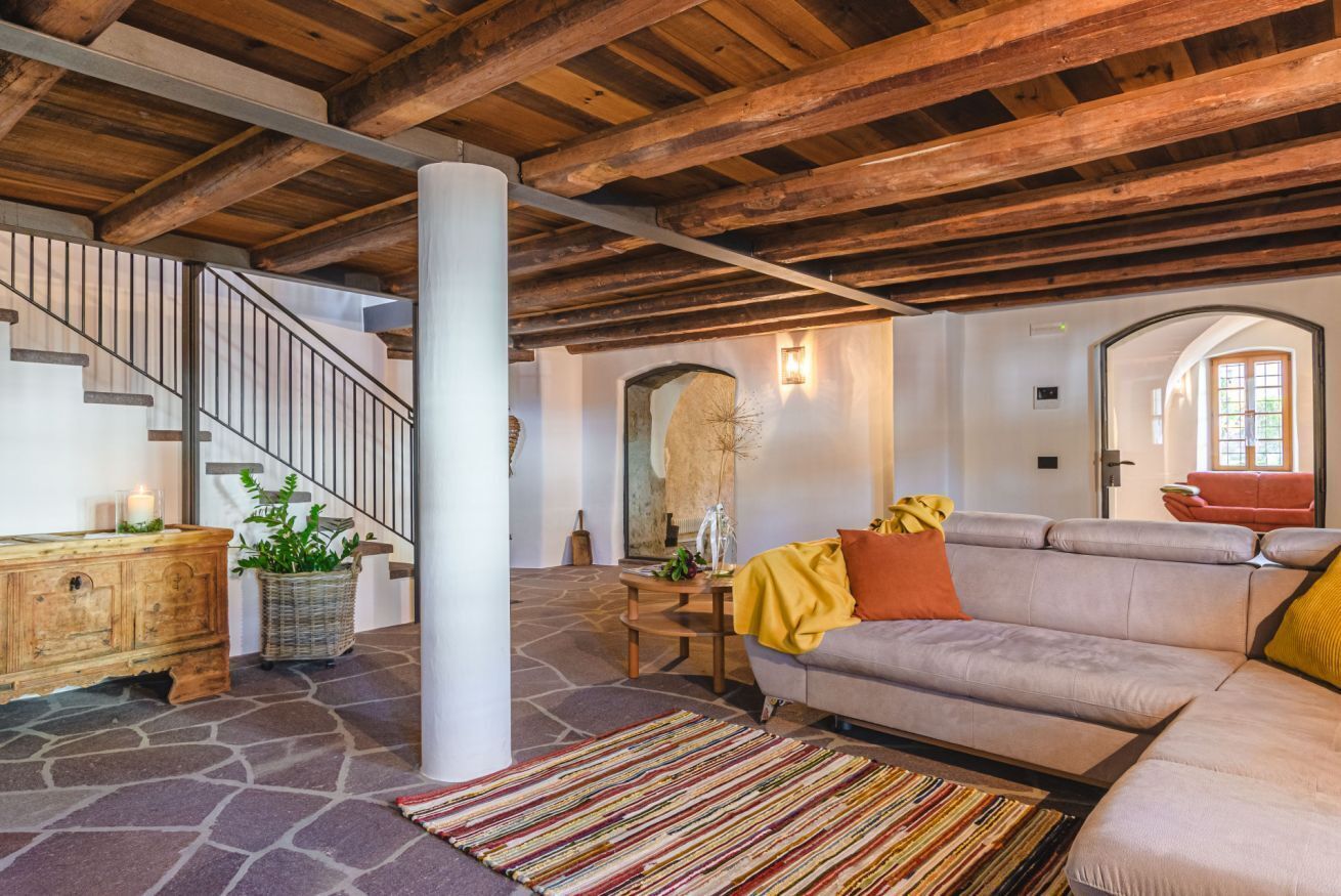 A spacious living area with a stone floor, a wooden staircase, and a modern sofa.
