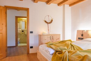 A bedroom with a wooden bed, a nightstand with candles, a wooden wardrobe, and a wall-mounted dreamcatcher. - Maso Strada Vecchia - un rifugio a metà fra il lago e la montagna (Auer)