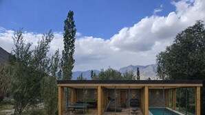 Estructura moderna al aire libre con piscina, equipo de ejercicio y vistas a montañas.