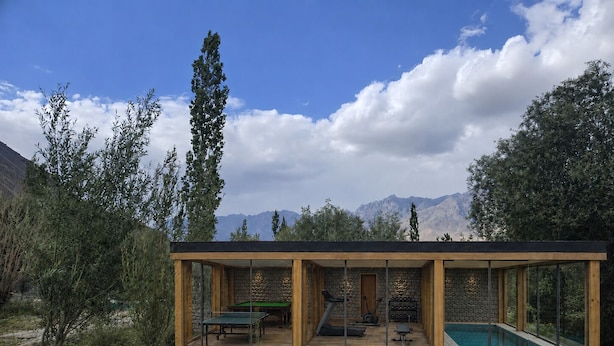 Estructura moderna al aire libre con piscina, equipo de ejercicio y vistas a montañas.