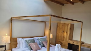 Una cama con dosel de madera, un tapete estampado y una mesita de noche con una lámpara.