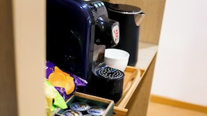 Una cafetera, una taza y una caja de sobres de café instantáneo.