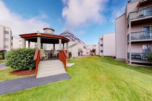 A residential building with a covered outdoor seating area, a small garden, and a pathway leading to the entrance. - Ski, Soak & Relax | Cozy Beech Mountain Condo (Beech Mountain)