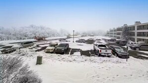 A parking lot with snow-covered cars and a building in the background. - Ski, Soak & Relax | Cozy Beech Mountain Condo (Beech Mountain)