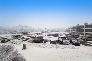A parking lot with snow-covered cars and a building in the background. - Ski, Soak & Relax | Cozy Beech Mountain Condo (Beech Mountain)